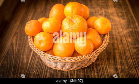 Frische reife Frucht tangerine Orangen in einem Korb mit Holz- Hintergrund. Stockfoto