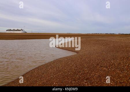 White Cottages und kurvig Schindel Banken um eine salzige Lagune bei Shingle Street, Suffolk, Großbritannien. Stockfoto