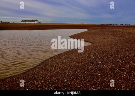 White Cottages und kurvig Schindel Banken um eine salzige Lagune bei Shingle Street, Suffolk, Großbritannien. Stockfoto