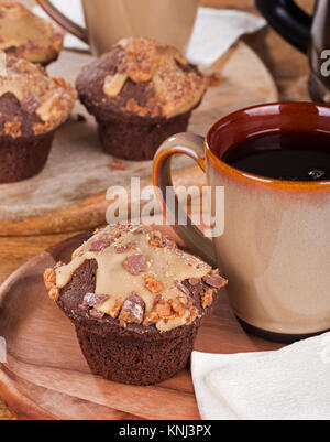 Peanut Butter Chocolate Cupcakes mit Zuckerglasur und Chips und Tasse Kaffee Stockfoto