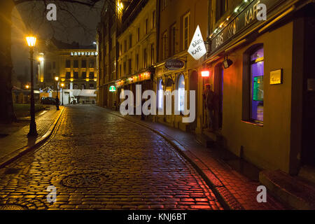 Bars und Cafes auf einer gepflasterten Straße in der Nacht in Riga, Lettland. Stockfoto