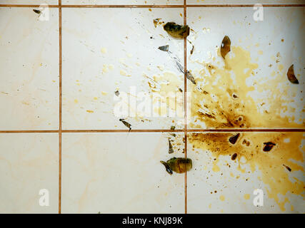 Bunte Flecken und Glasscherben auf weißen Fliesen im Bad. Stockfoto