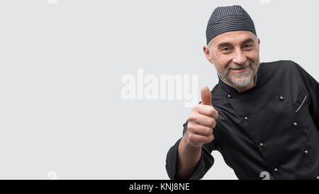 Erfolgreiche reifen Koch posiert mit Daumen nach oben und Suchen an Kamera Stockfoto