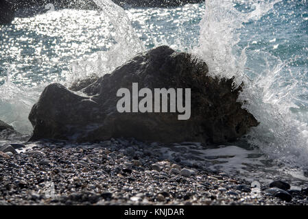 Wellen brechen über einen Felsen am Strand in der Nähe von Kardamyi Foneas, Westküste von Griechenland Stockfoto