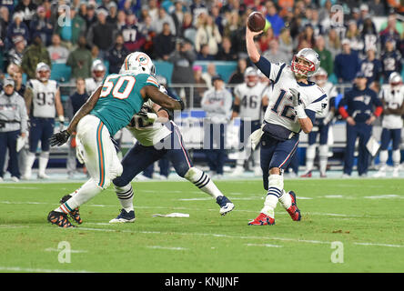 Miami Gardens, Florida, USA. 11 Dez, 2017. New England Patriots Quarterback Tom Brady (12) wirft den Ball als Miami Dolphins defensive Ende Andre Zweig (50) Drücke während der zweiten Hälfte des Spiel zwischen den New England Patriots und die Miami Dolphins im Hard Rock Stadion in Miami Gardens, Fla., am Montag, den 11. Dezember 2017. Endstand, Miami 27, New England, 20. Quelle: Andres Leiva/der Palm Beach Post/ZUMA Draht/Alamy leben Nachrichten Stockfoto