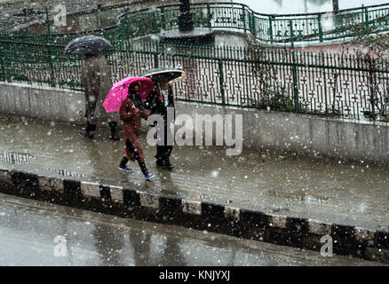 Srinagar, Indien verwaltet. Kaschmir. 13. DEZEMBER kaschmirischen Mädchen hält Regenschirm als Sie geht, während weiterhin Schneefall am zweiten Tag fünf Soldaten mitgerissen in starker Schneefall in der Nähe der Grenze Beiträge in Kupwara und Bandipora untraced nach mehr als 24 Stunden am Dienstag blieb. Schlechte Sicht und frischem Schneefall den Flugverkehr in Srinagar Flughafen am Mittwoch betroffen, Berichte sagte. Eine offizielle, sagten Sie, dass kein Flug von Srinagar Internationalen Flughafen wegen und schlechte Sichtverhältnisse und leichtem Schneefall betrieben hat. © sofi Suhail/Alamy leben Nachrichten Stockfoto