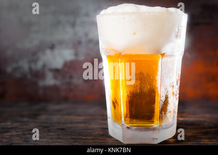 Grosses Glas mit hellem Bier und ein großer Kopf, der Schaum auf alten, dunklen Schreibtisch. Trinken und Getränke Konzept Stockfoto