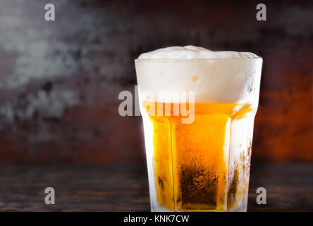 Grosses Glas mit hellem Bier und eine Schaumkrone auf alten, dunklen Schreibtisch. Trinken und Getränke Konzept Stockfoto