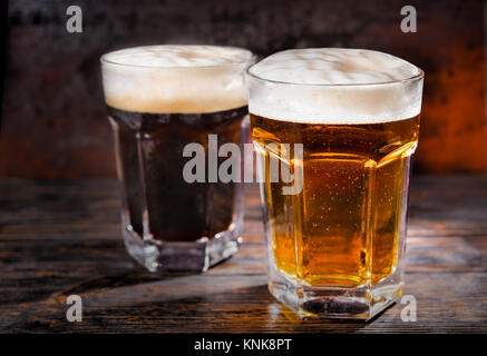 Zwei große Gläser mit frisch gegossen und dunklen Bier und Leiter der Schaum auf Holzschreibtisch. Nahrungsmittel und Getränke Konzept Stockfoto