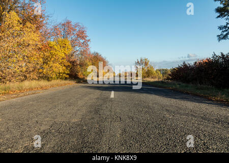 Leere Herbst Straße entlang golden Winterweizen Felder bei Sonnenuntergang Stockfoto