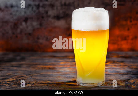 Grosse frozen Glas mit frisch gezapften Licht ungefilterte Bier und Leiter der Schaum auf dunklem Holzschreibtisch. Nahrungsmittel und Getränke Konzept Stockfoto