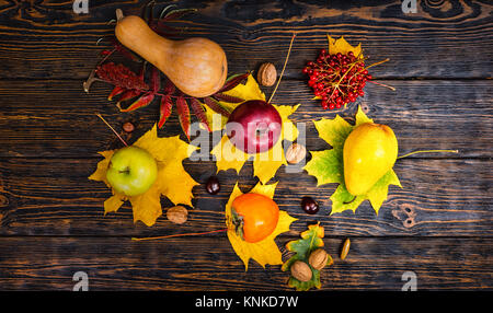 Blick von oben auf die schöne Ernte der Äpfel, Nüsse, Rowan, Kürbis und Persimmon liegen auf Blätter. Thanksgiving Day und Herbst Konzept Stockfoto