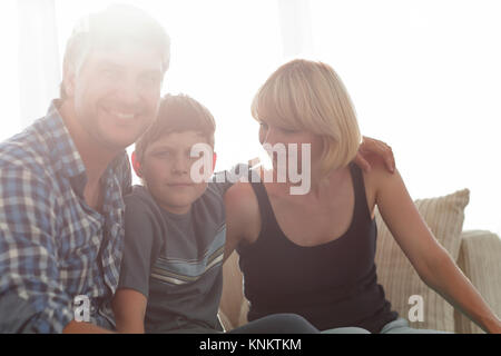 Eltern und ihren Sohn im Wohnzimmer zusammengekauert sitzen und Lächeln Stockfoto