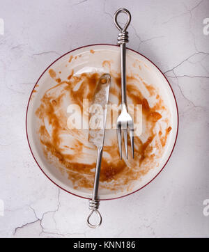 Teller der Reste mit Messer und Gabel flatlay auf einem Marmor Hintergrund. Stockfoto