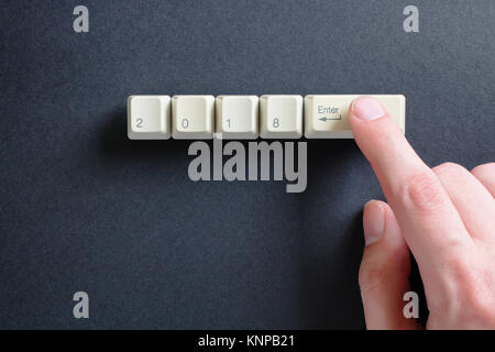 Zeigefinger der Hand drückt man auf der Tastatur, auf dem 2018 geschrieben und Ket auf einem schwarzen Hintergrund ein. Neues Jahr 2018 Karte. Stockfoto