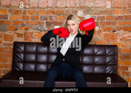 Attraktive Blondine Geschäftsfrau mit Boxhandschuhen für einen Kampf vor eine Wohnung bereit. Geschäftskonzept. Stockfoto