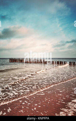 Vintage getonten Bild einer alten hölzernen Wellenbrecher am Strand bei Sonnenuntergang, Natur Hintergrund. Stockfoto
