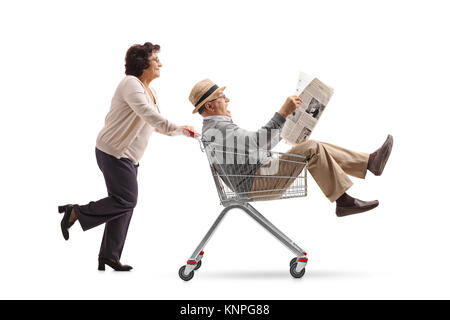 Ältere Frau treibt ein Warenkorb mit einem reifen Mann, innerhalb und las eine Zeitung auf weißem Hintergrund Stockfoto