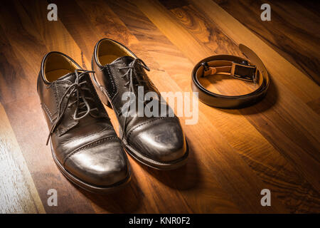Elegante schwarze Handgefertigte Kleidung Schuhe und Leder Riemen auf Holzboden Spotlight Sun Kleidung Stockfoto