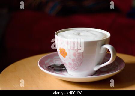 Tasse Kaffee mit Milchschaum in Becher auf Holztisch auf hellen Sonntag Morgen Stockfoto