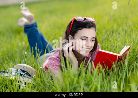 Junge Frau Liegt Mit Buch in der Wiese - Frau mit Buch in der Wiese liegend Stockfoto