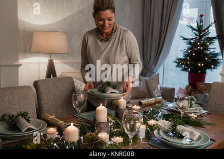 Glückliche Mutter ist die Einstellung der Tabelle für Weihnachten Abendessen mit Ihrer Familie. Stockfoto