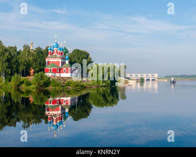 Rote Kirche mit blauen Kuppeln von uglitsch Stadt am Ufer umgeben von grünen Bäumen, Blick von der Wolga an sonnigen Sommertag Stockfoto