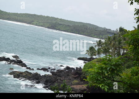 Meerblick vom Berg. Meer, Bäume und Berge. Rocky mit Meerblick mit Kokospalmen in der Seite. Meer von Grün und Bergen umgeben. Stockfoto