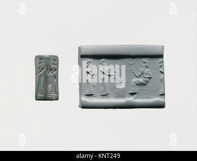 Zylindersiegel, der einen Gläubigen darstellt, der vor einer sitzenden Gottheit einen Trankopfer ausgießt, mit einem modernen Eindruck, der geschnitzte Details und symbolische Elemente zeigt. Stockfoto