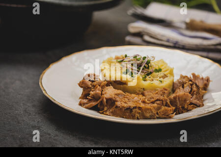 Confit Schweinekamm mit Kartoffelpüree auf steinernen Tisch Stockfoto