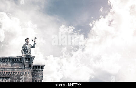 Unternehmer oder Manager auf dem Dach des Gebäudes etwas verkünden in Stockfoto