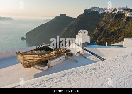 Boot auf einem Hausdach bei Sonnenuntergang vor skaros Felsen am Dorf Imerovigli, Santorin Stockfoto