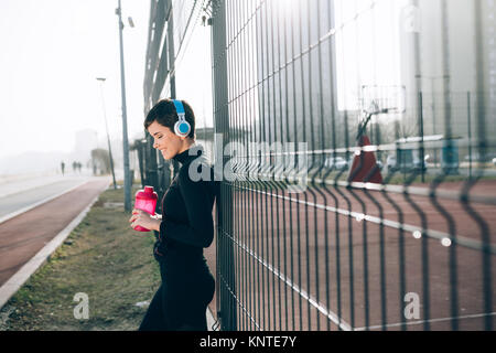 Frau hören von Musik während der Arbeit aus und Joggen im Freien Stockfoto