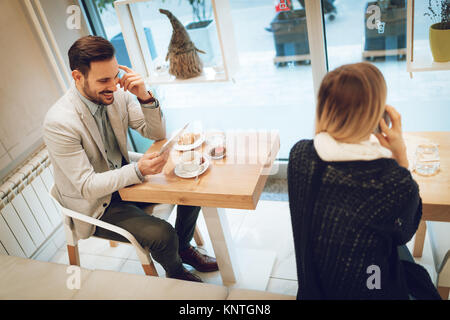 Junge Geschäftsleute, die sich auf eine Pause in einem Cafe. Lächelnde Menschen surfen im Internet bei digital Tablet und Frühstücken. Frau mit Smartphone. Selektive Stockfoto