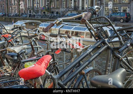 Abgestellte Fahrräder in der Nähe von einem Kanal mit anstehenden Ausbau Hinweise auf der Fahrräder in Amsterdam, Niederlande Stockfoto