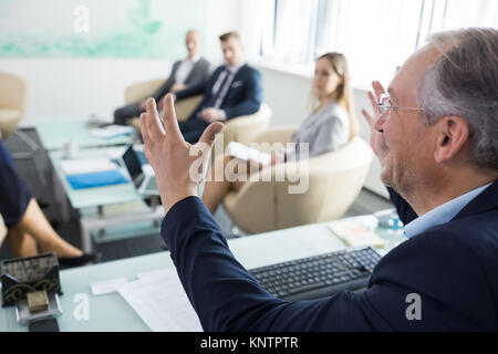Senior Geschäftsmann gestikuliert während der Diskussion mit Führungskräften im Tagungsraum im Büro Stockfoto