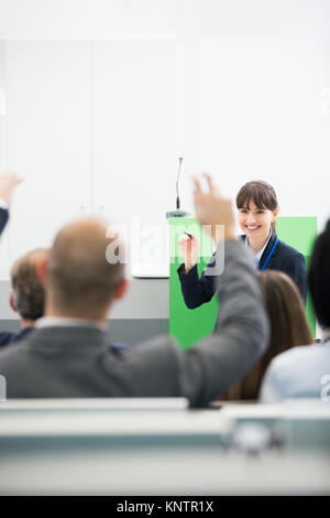 Lächeln, Geschäftsfrau, Fragen zu Kollegen, während sie eine Präsentation im Vortragssaal Stockfoto