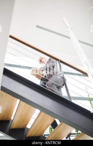 Low Angle View der Geschäftsmann mit digitalen tablet, während im Obergeschoss im Büro Stockfoto