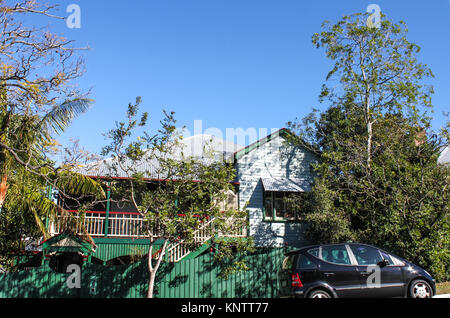 Traditionelle australische Queenslander House in Grün und Rot auf einem Hügel mit hohen Gummi Bäume und ein Auto draußen geparkt Stockfoto