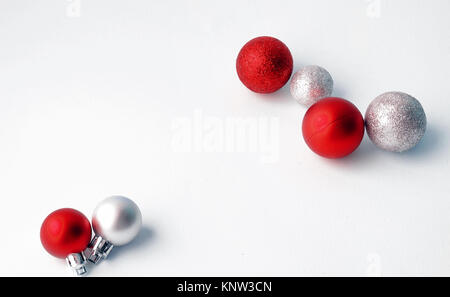 Weihnachtsbaum Spielzeug auf einem weißen Hintergrund. Weihnachten Dekorationen auf eine weiße Fläche. Kugeln und girlande von Rot und Silber Farben auf dem Tisch. Stockfoto