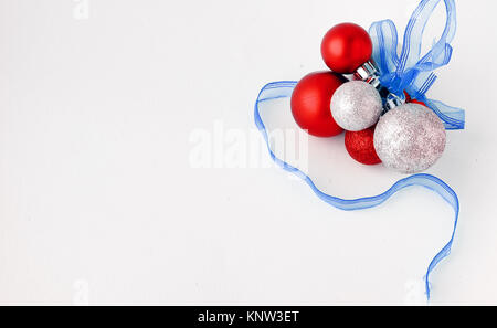 Weihnachtsbaum Spielzeug auf einem weißen Hintergrund. Weihnachten Dekorationen auf eine weiße Fläche. Kugeln und girlande von Rot und Silber Farben auf dem Tisch. Stockfoto