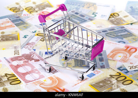 Stapel von Euro-banknoten mit Warenkorb in Geld verbrauchen Konzept, auf volle Hintergrund. Stockfoto