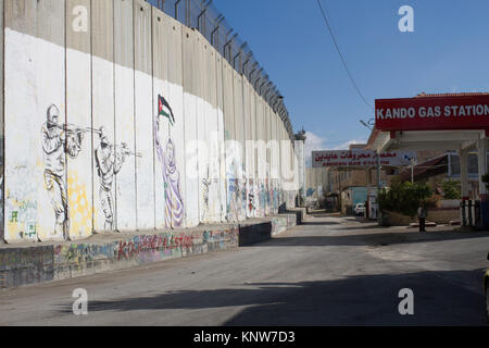 Wall Art, israelische Soldaten, die Waffen auf eine palästinensische Frau auf der Trennmauer in Bethlehem, West Bank, Palästina Stockfoto