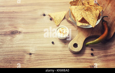 Mais Chips in der jar. Traditionelle Snack für Bier mexikanische Nachos. Nachos mit Gewürzen und Pfeffer auf Holztisch. Stockfoto