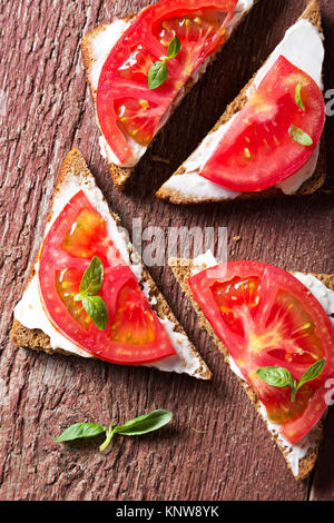 Sommer Sandwiches mit Tomaten und Basilikum auf einer hölzernen Oberfläche. Stockfoto