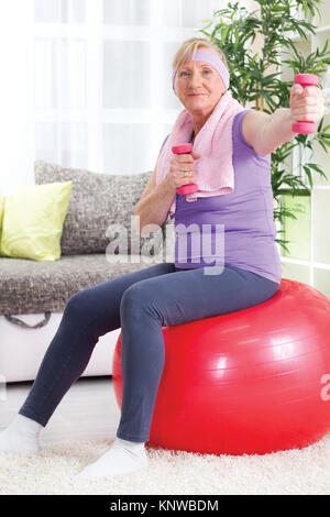 Ältere Frau sitzt auf der Gymnastikball, und Übung Stockfoto