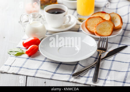 Weiße Platte, Kaffee und Orangensaft auf einem weißen Holztisch. Serviert zum Frühstück Stockfoto