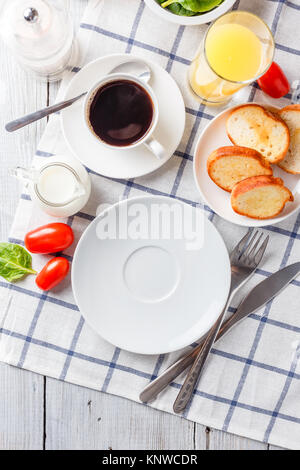 Weiße Platte, Kaffee und Orangensaft auf einem weißen Holztisch. Zum Frühstück servieren. Ansicht von oben Stockfoto