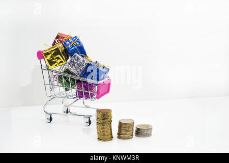 Abstrakte Komposition von etwas zu kaufen. Kleine Wagen mit Münzen auf weißem Hintergrund. Stockfoto