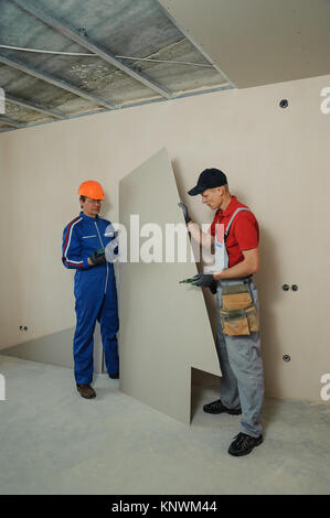 Drywall Installers. Men holding a gypsum board figured cut Stockfoto